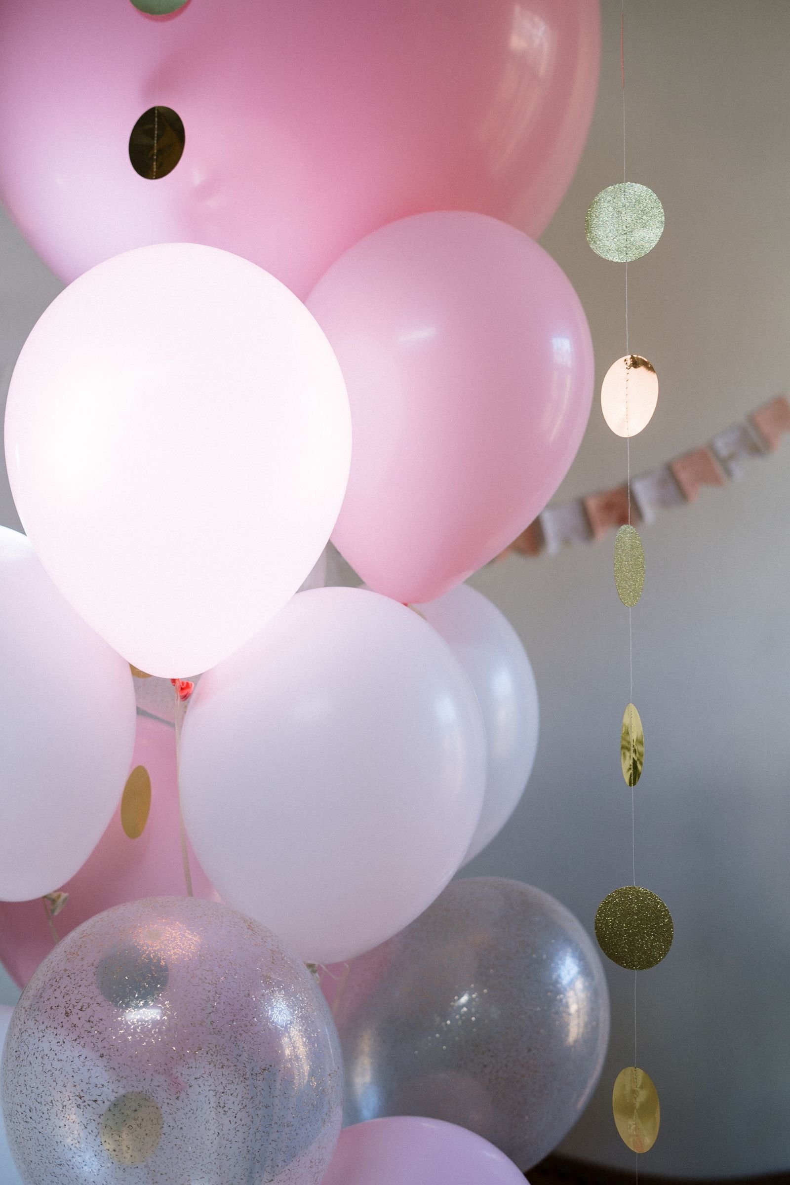 Pink and white balloons with glitzy decorations on a ceiling.