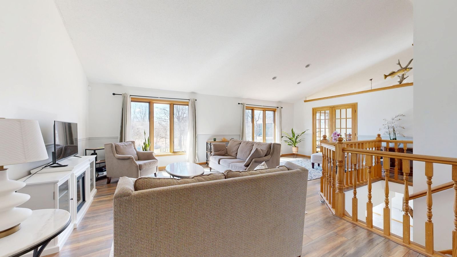Bright living room with neutral furnishings and large windows.