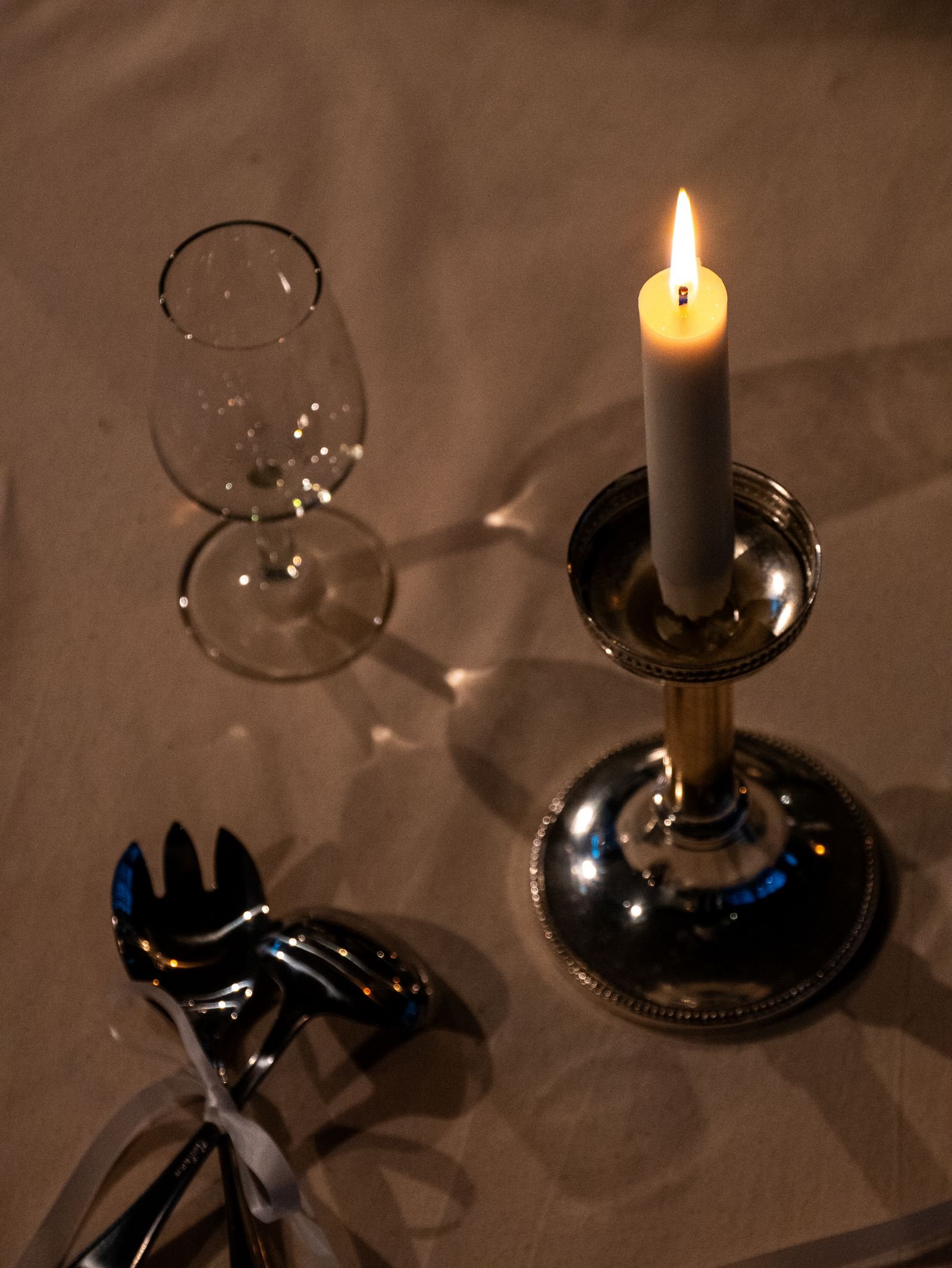 Candlelit table set with silverware and a wine glass.