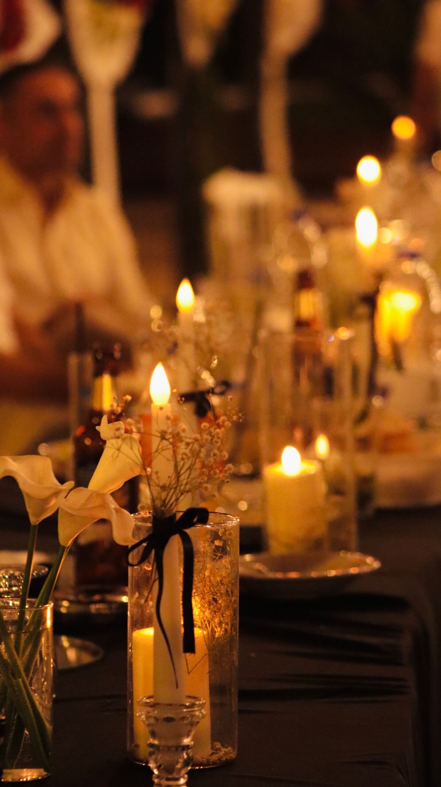 Candlelit dinner table with fresh flowers and glassware.