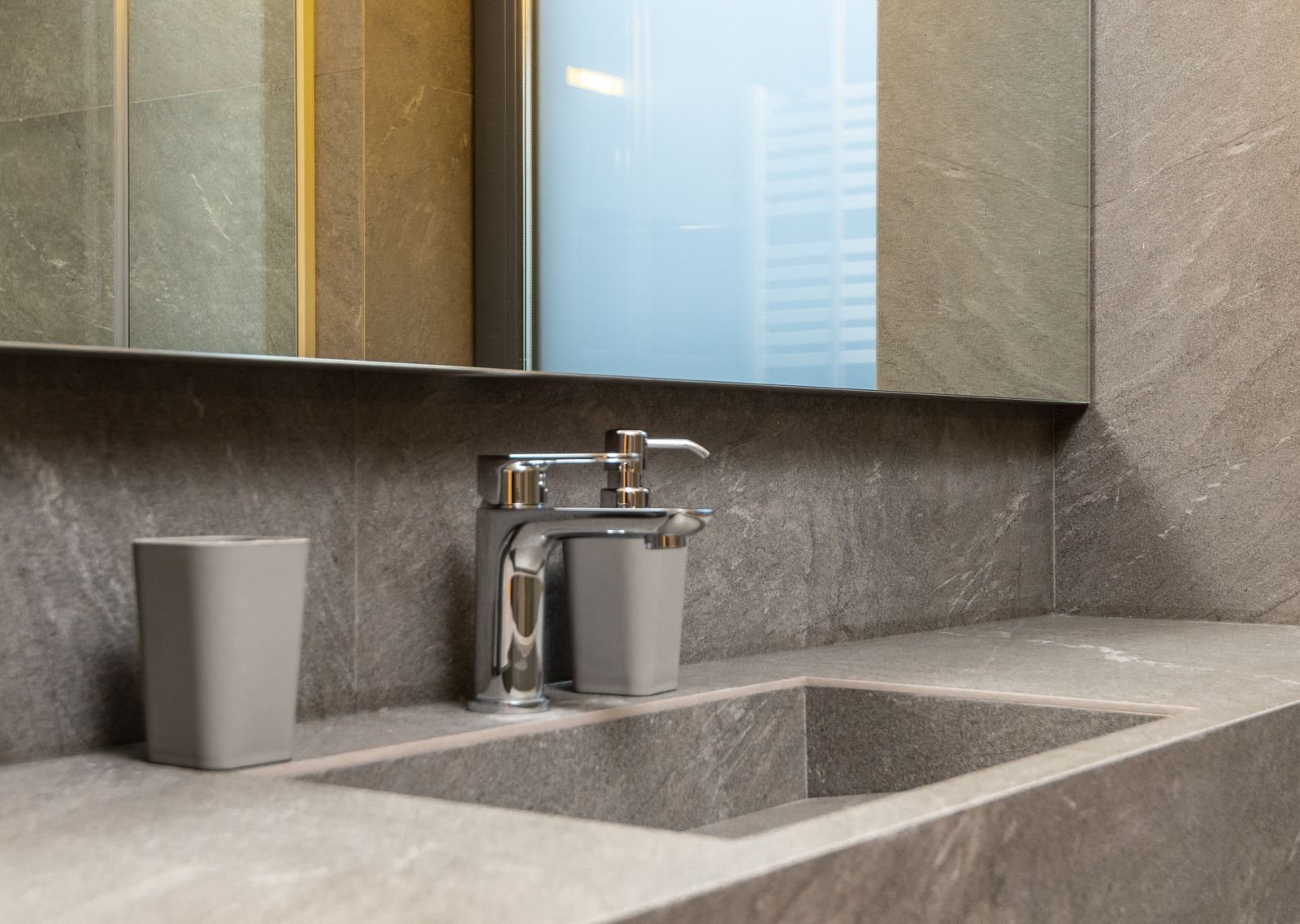 Chrome faucet and marble sink under a mirror.
