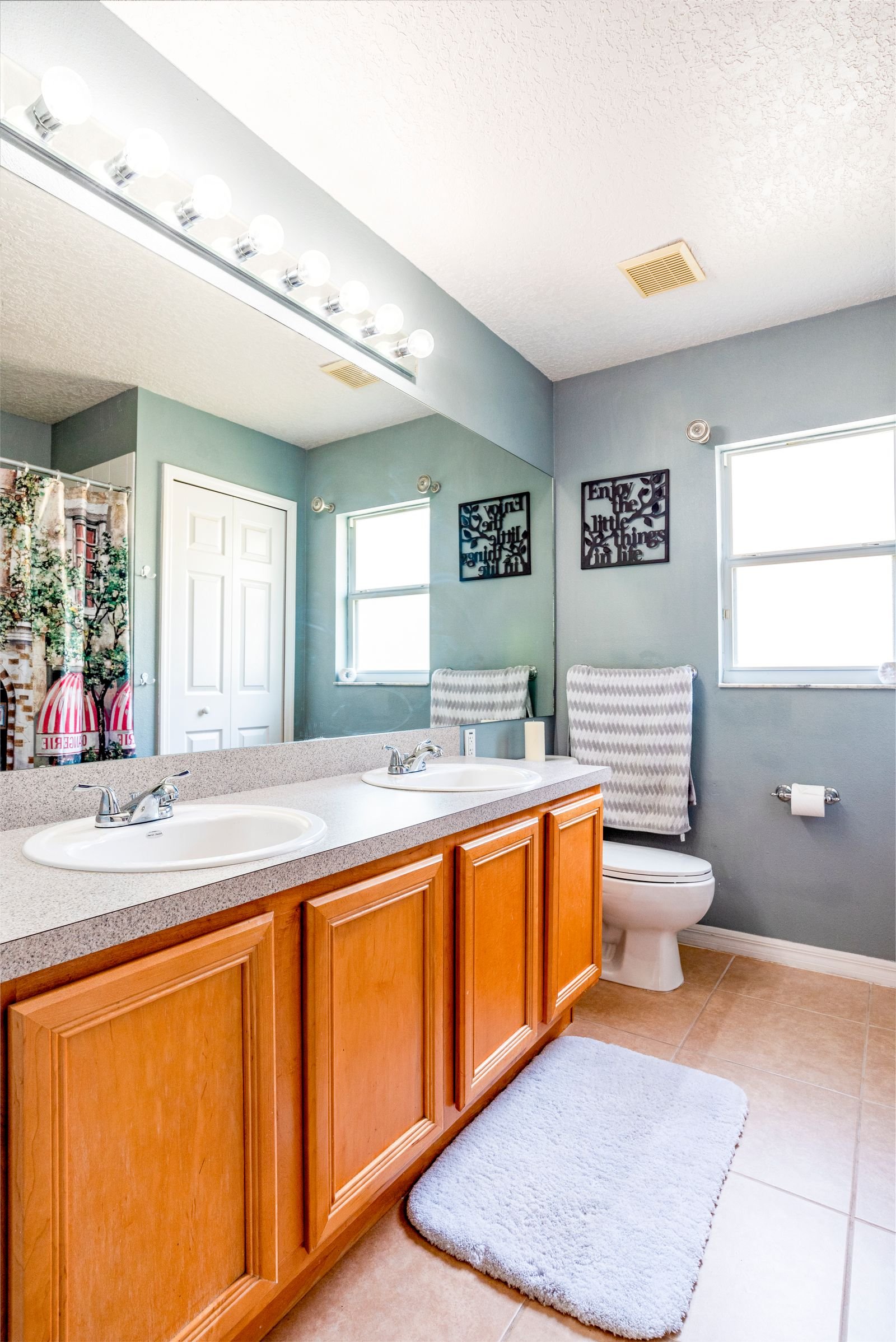 Bright bathroom with wooden cabinets, a large mirror and natural light.