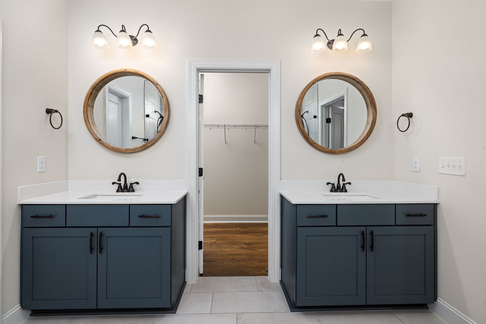 Modern bathroom with two sinks, round mirrors and soft lighting.