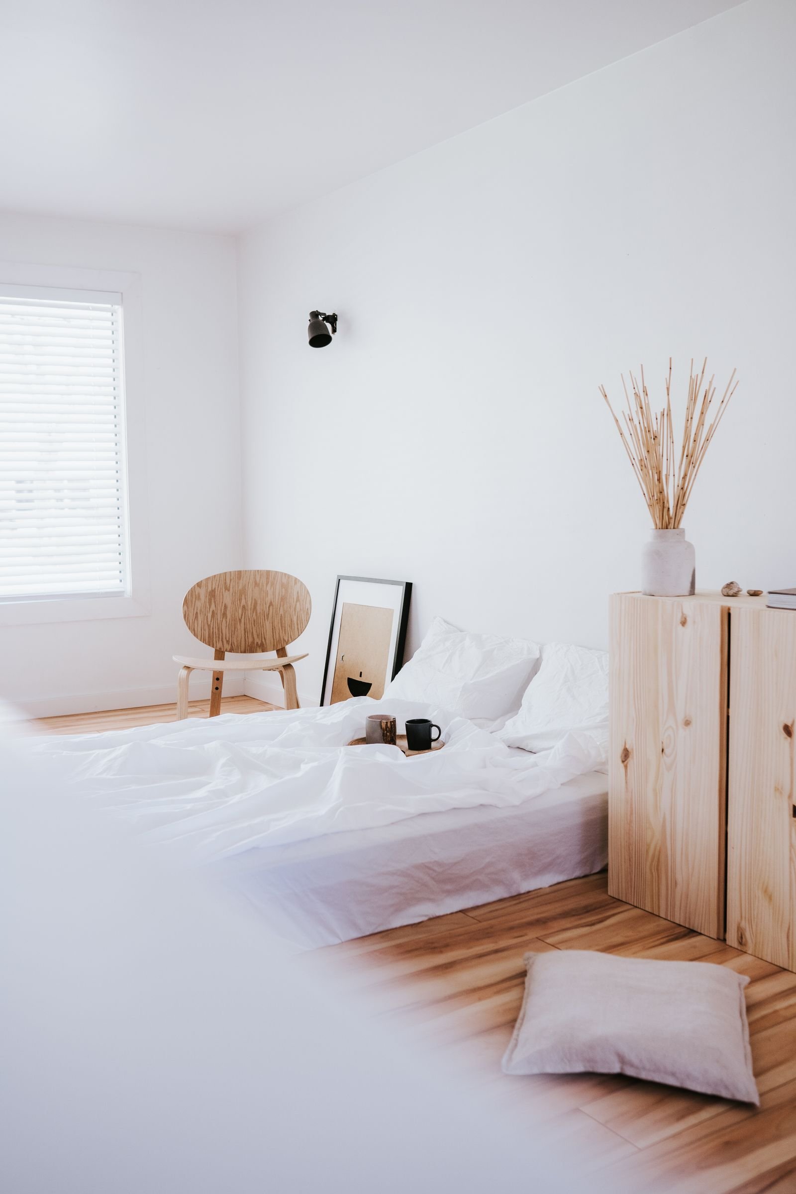 Bright minimalist bedroom with pale walls and wooden accents.