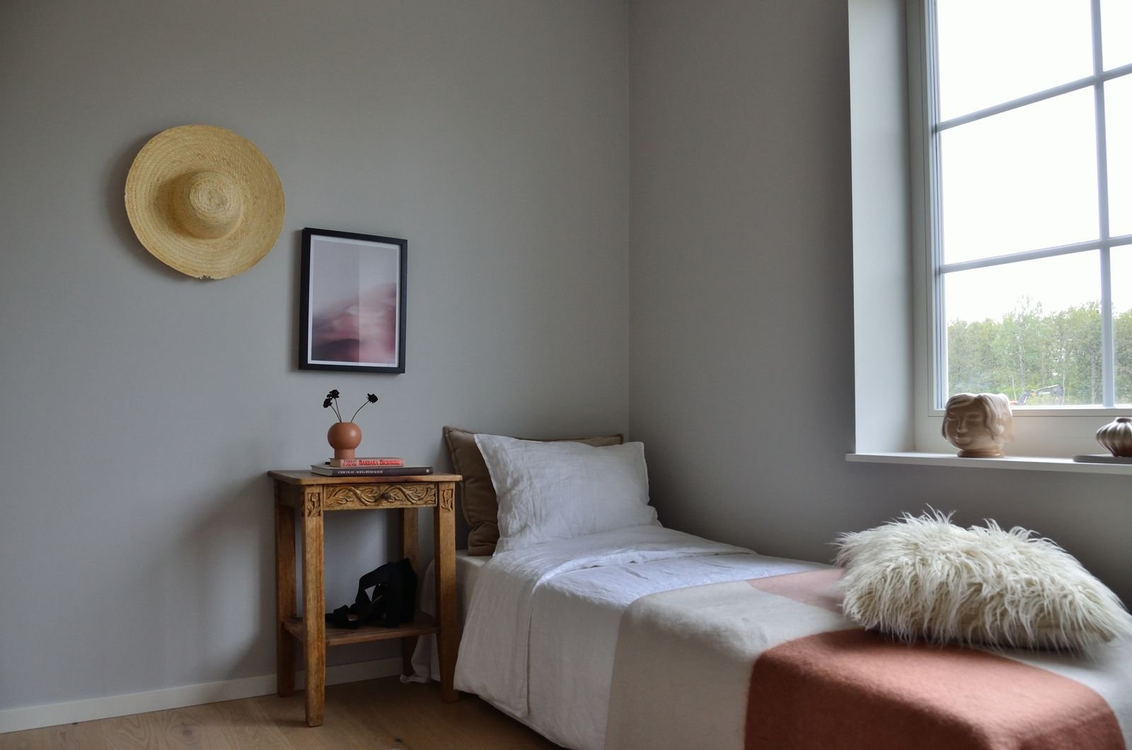 White bed linen on a wooden bed frame in a minimalist bedroom.