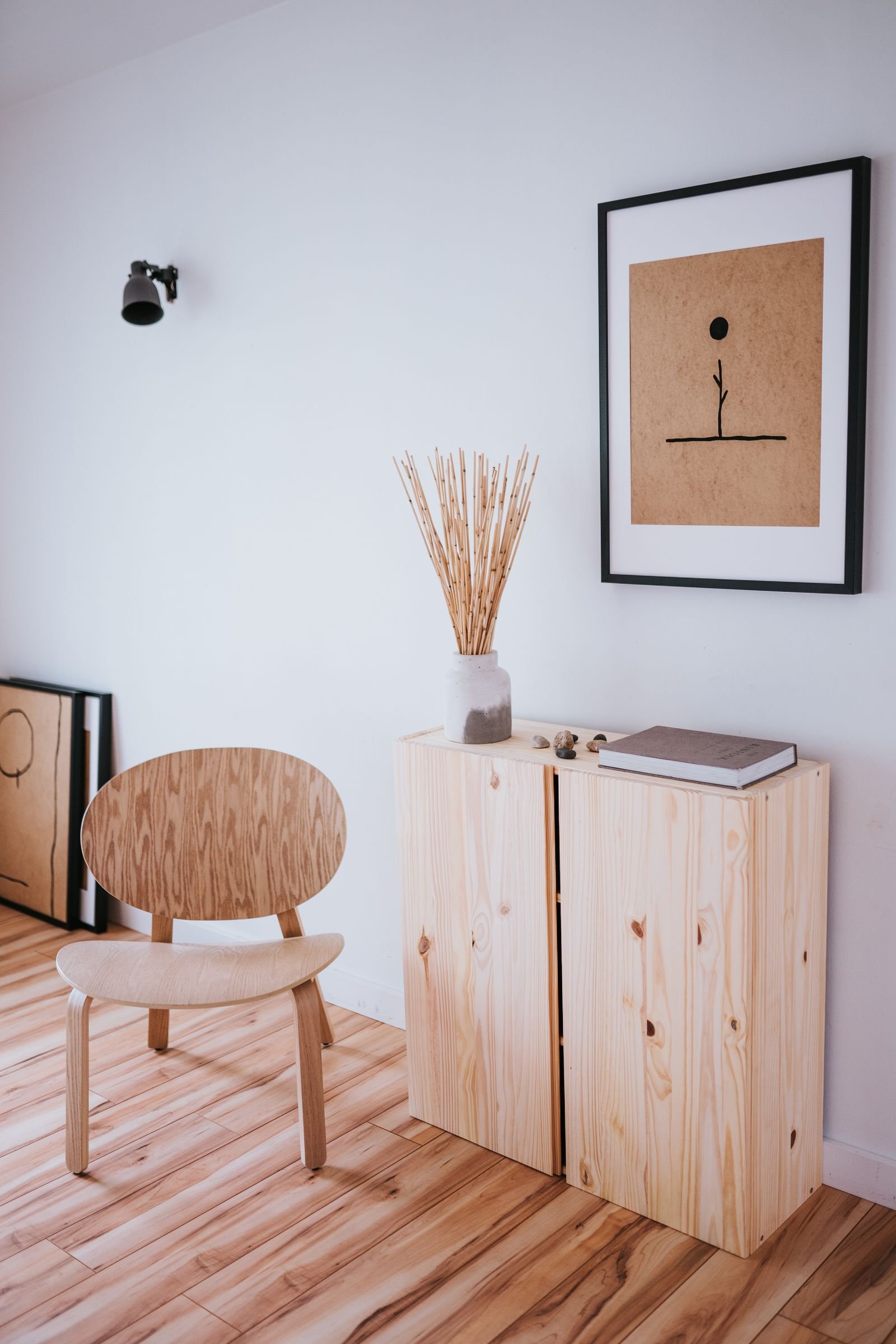 Calm room with a wooden cabinet, brown chair and minimalist art.