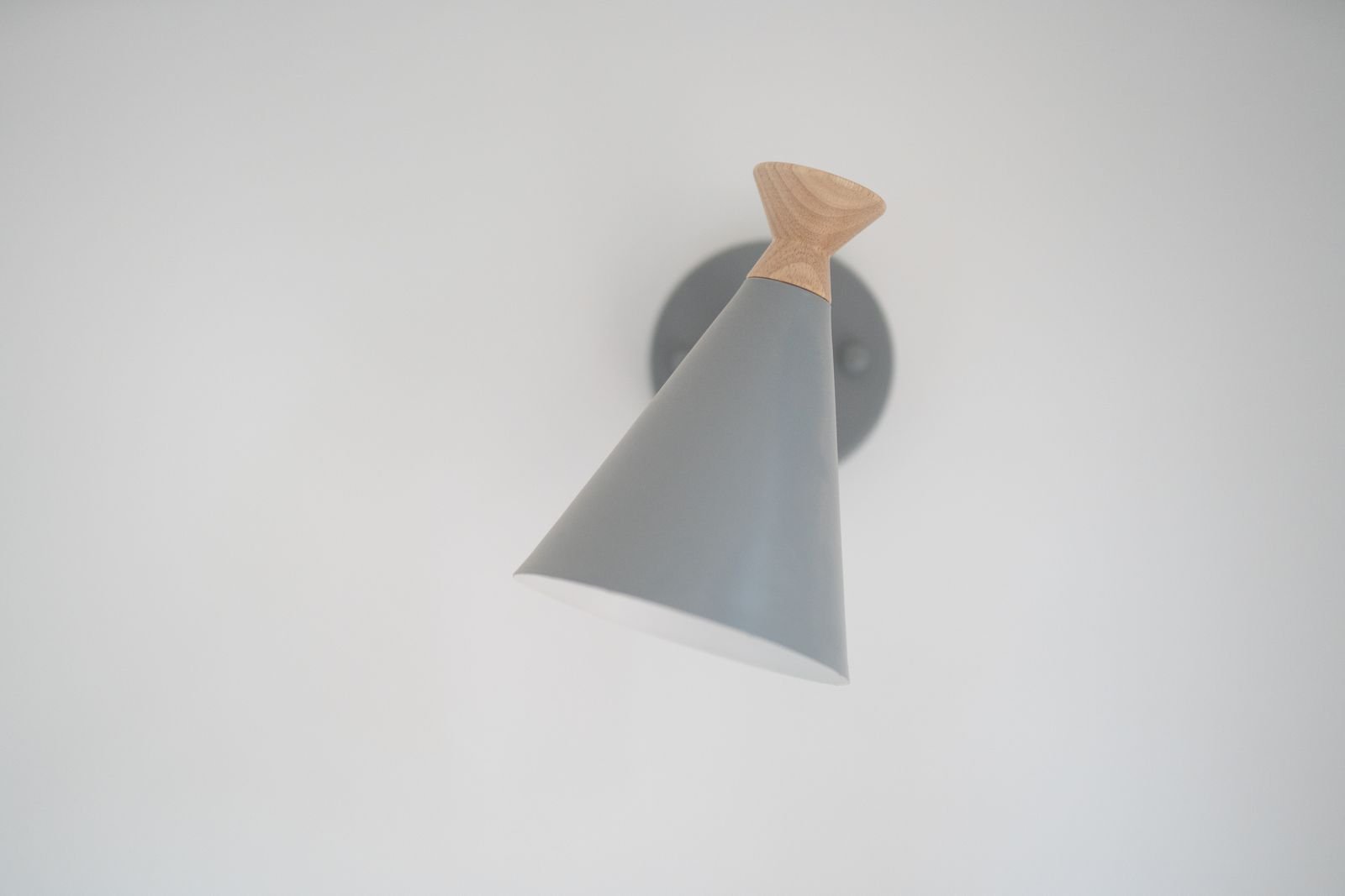 Cone-shaped wall lamp with wood accents on a white wall.