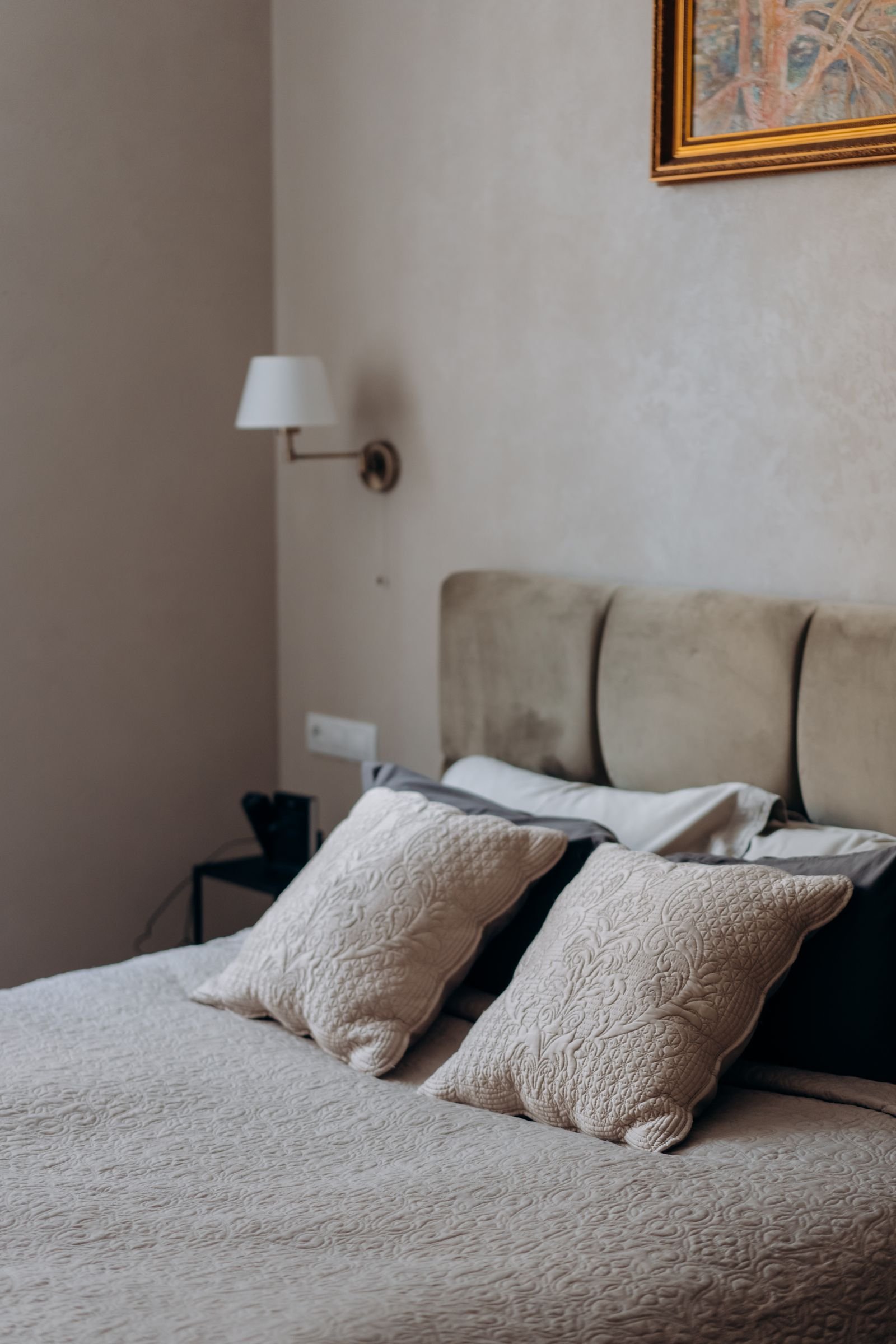 Minimalist bedroom with neatly arranged pillows and wall art.