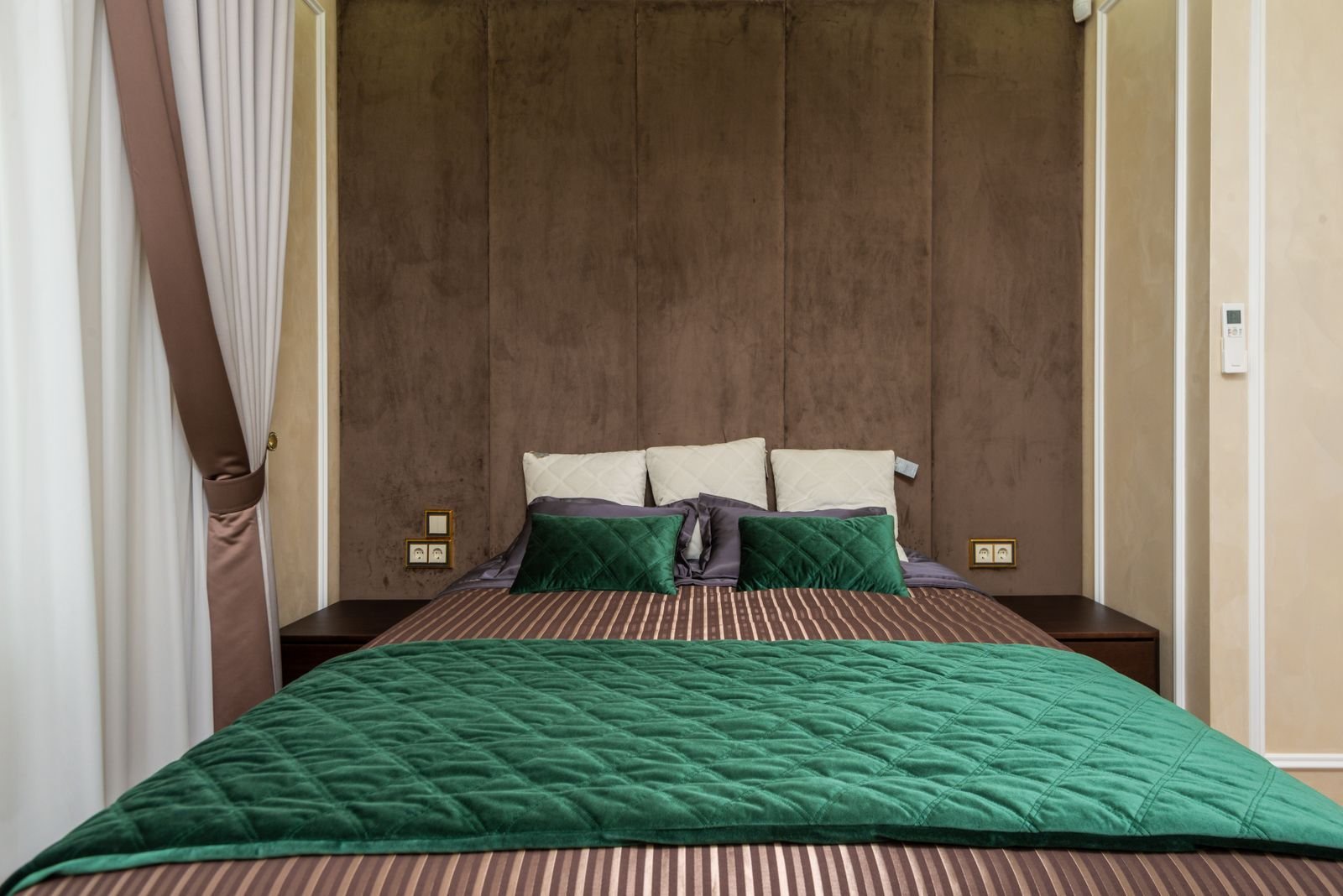 Modern bedroom with green bedding and soft lighting.