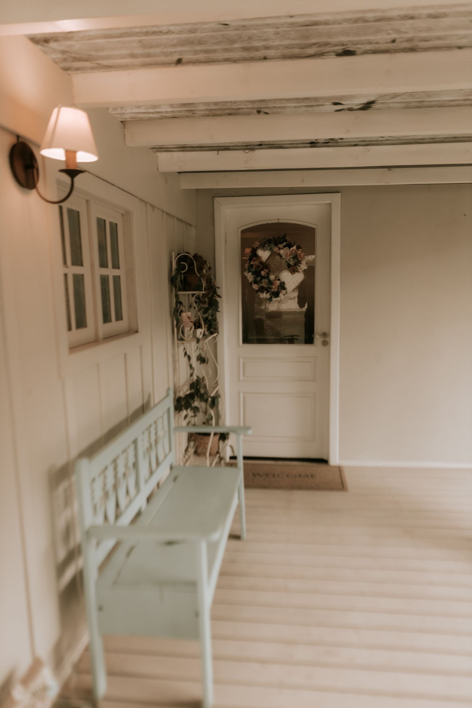 Small rustic porch with a wreath on the front door and a wooden bench.