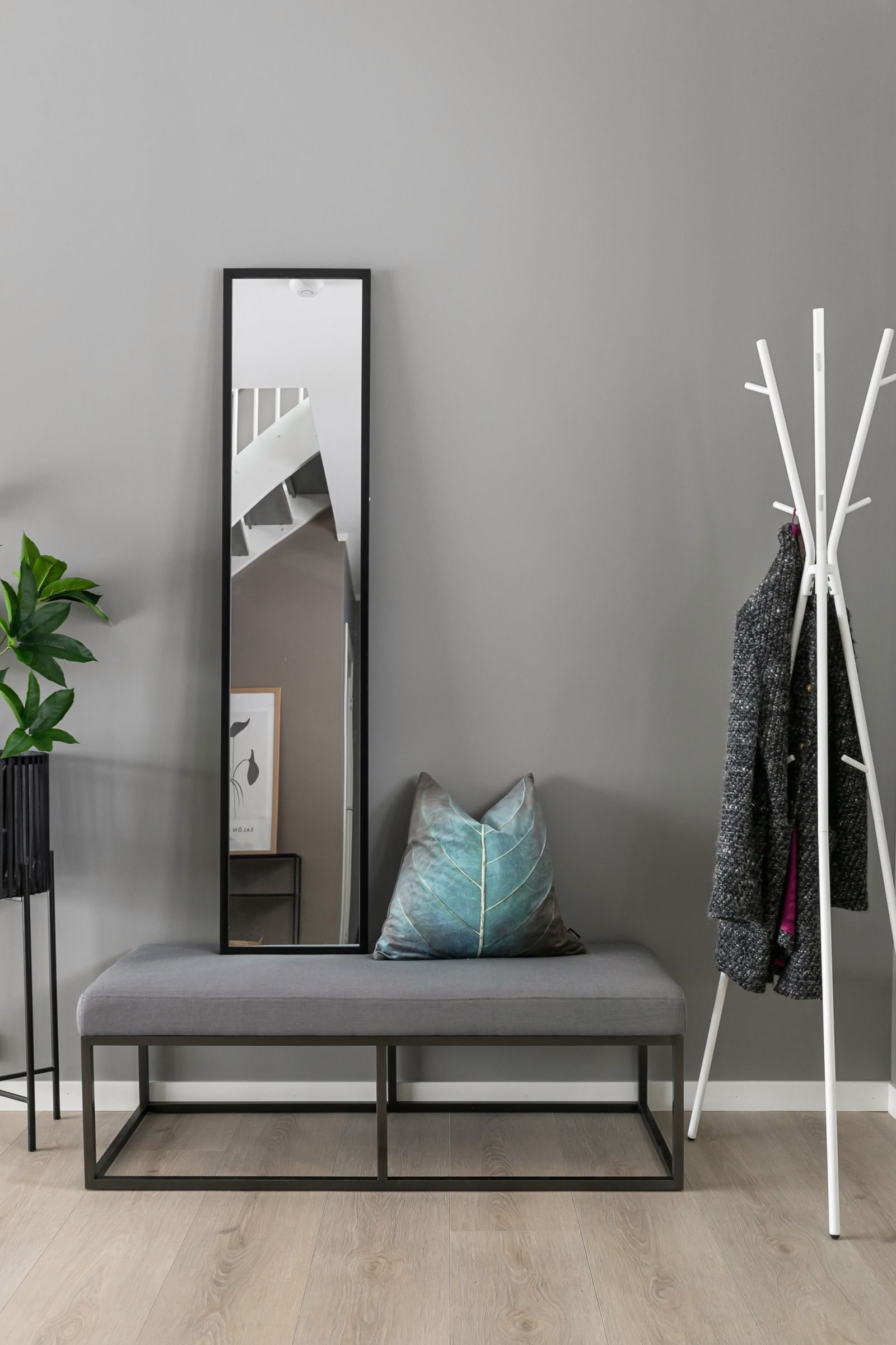 Narrow hallway with a wall mirror, a coat rack and a bench.