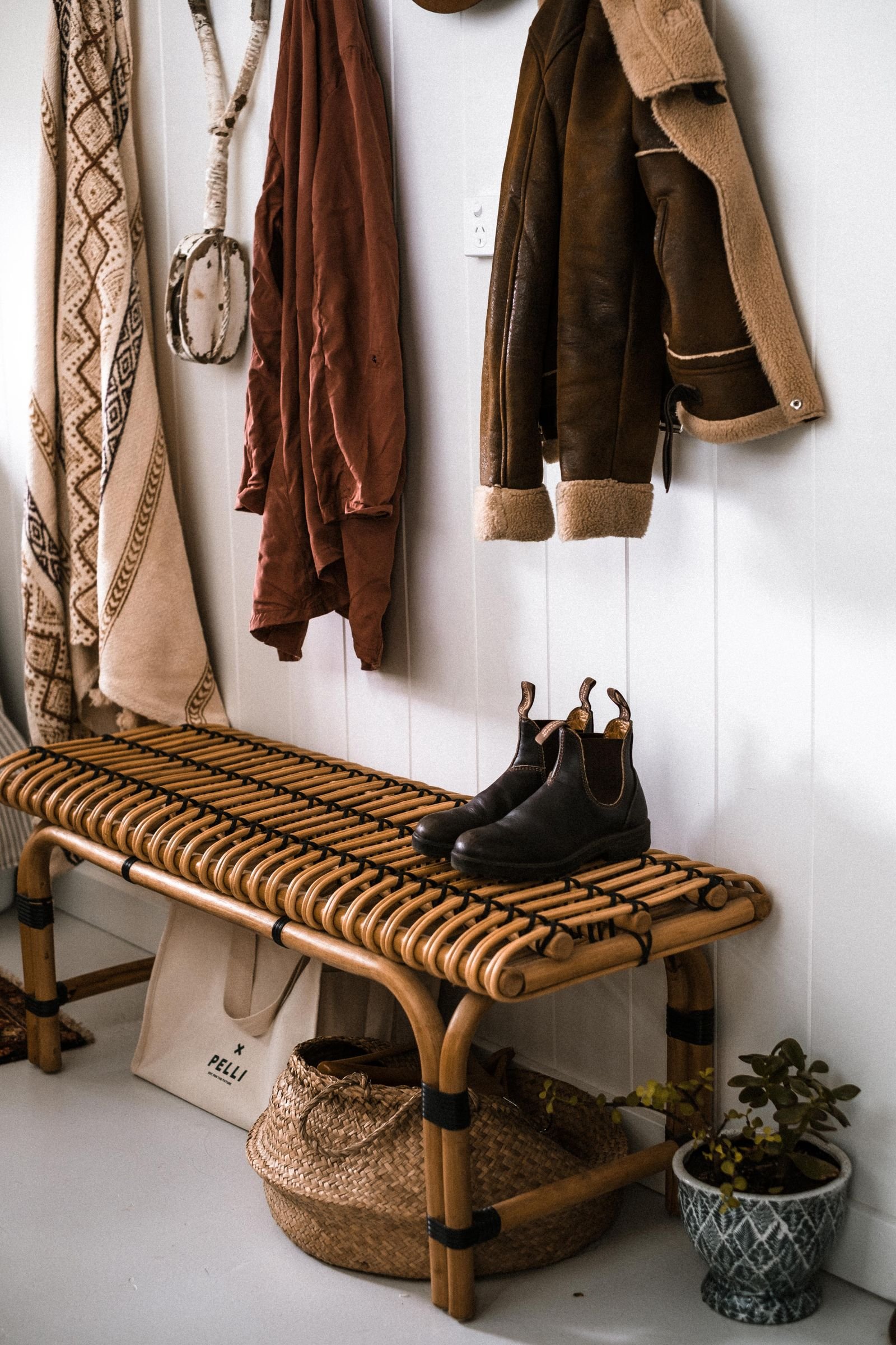 Rustic entryway with a woven bench, wall hooks and hanging coats.