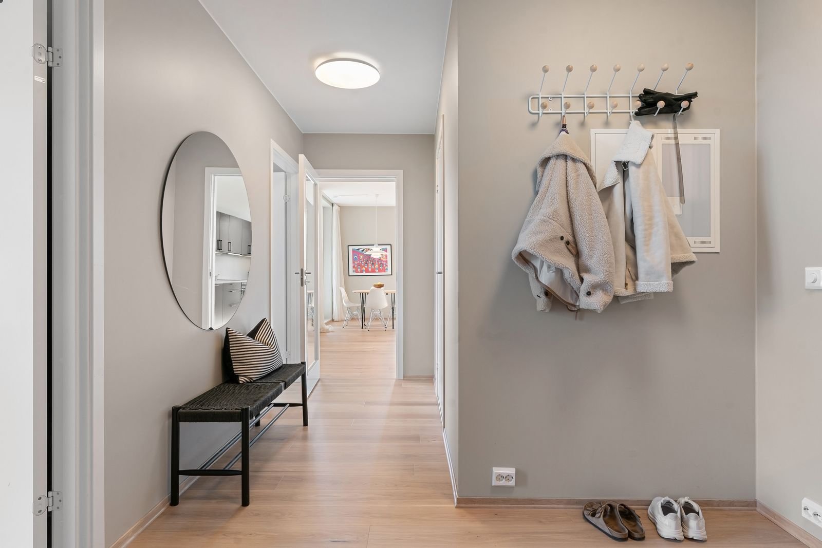 Compact minimalist hallway with a mirror, coats and shoes by the door.