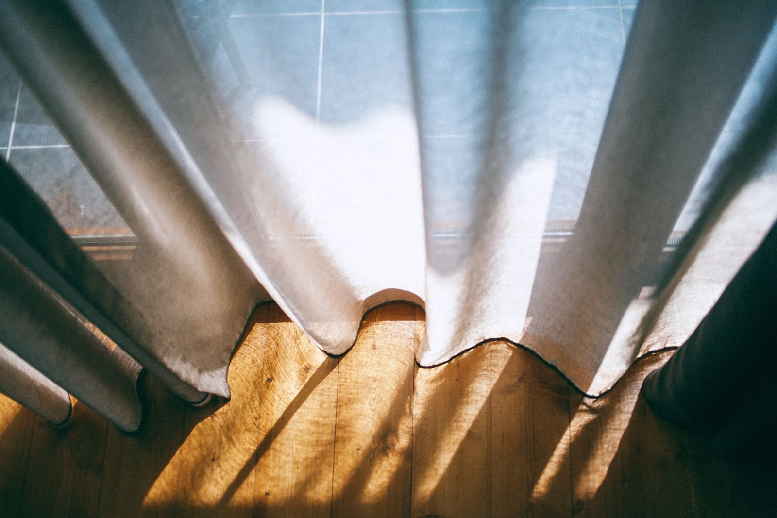 Sheer white curtains at a large window filled with sunlight.