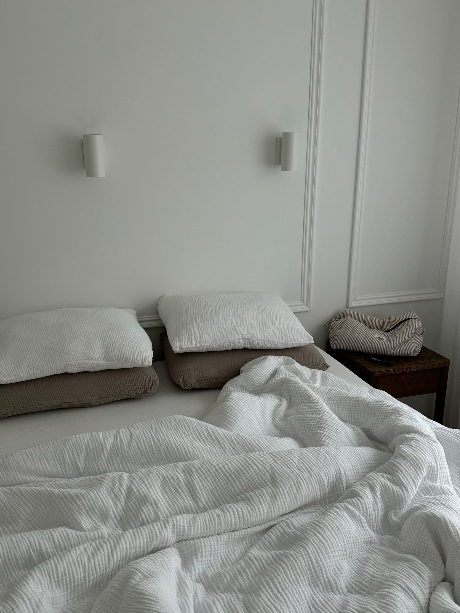 Minimalist white bedroom with soft, crumpled bedding.