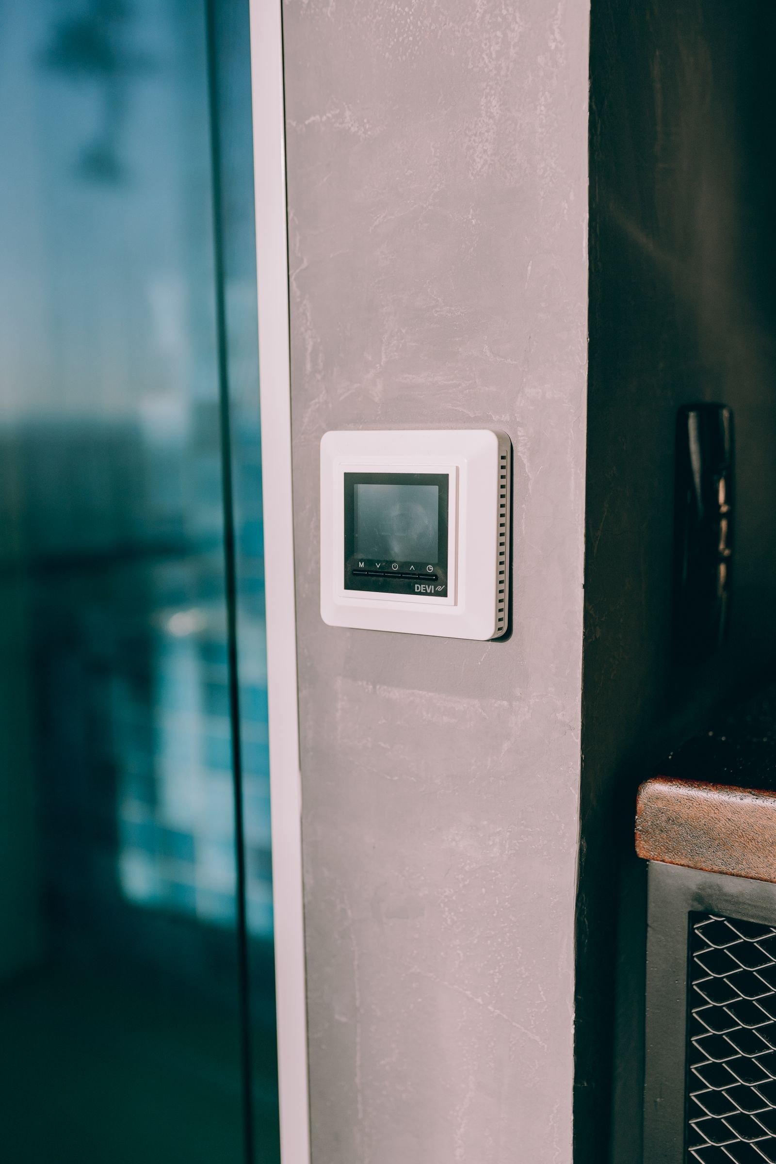 Digital thermostat on a wall beside a sunny window