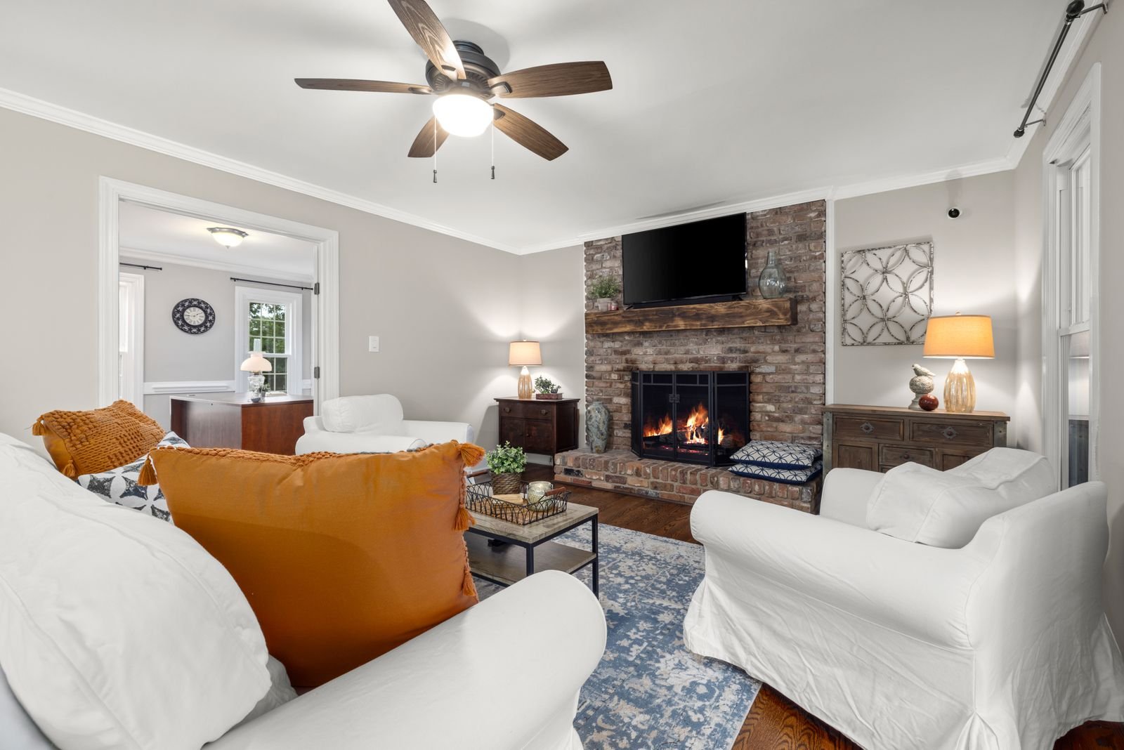 Living room with a warm brick fireplace, orange accents and classic earthy decor.