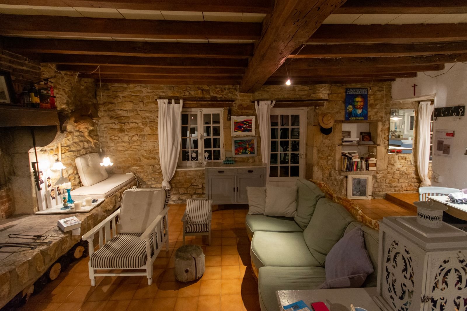 Rustic living room with stone walls, wooden beams, armchairs and a sofa.