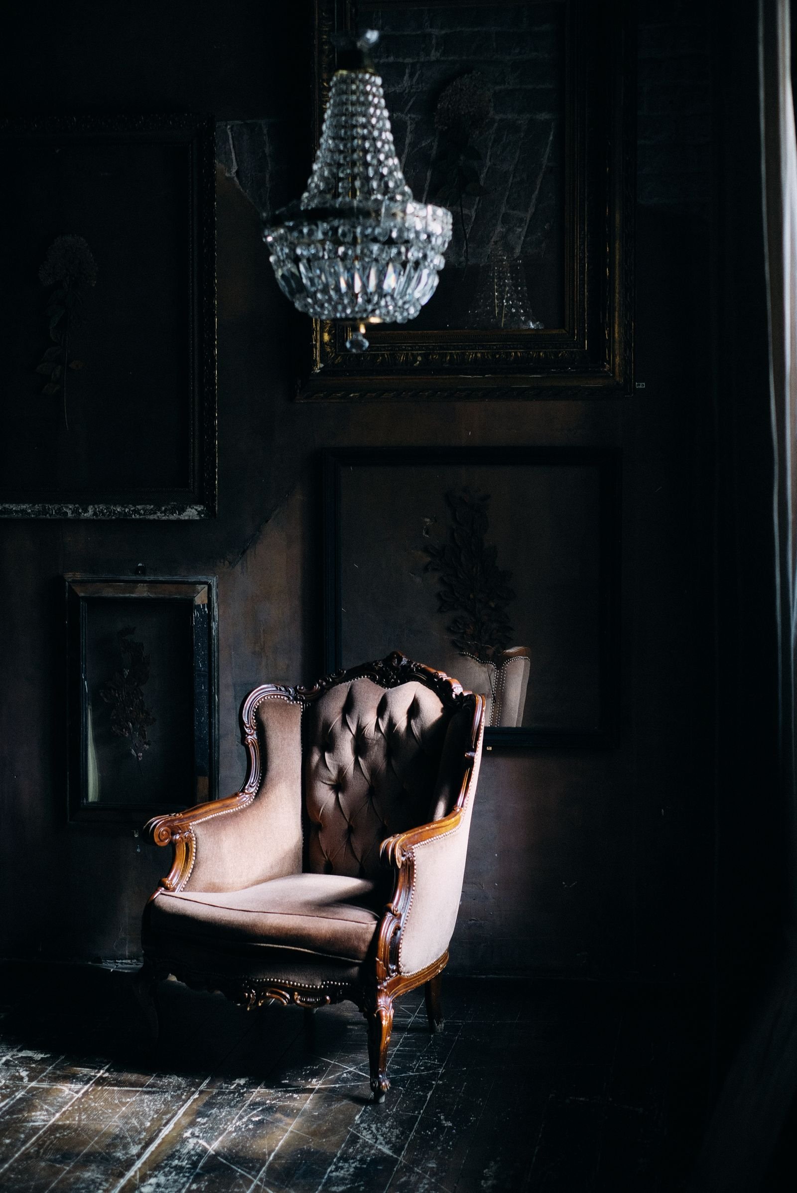 Vintage armchair beneath a chandelier in a softly lit room.