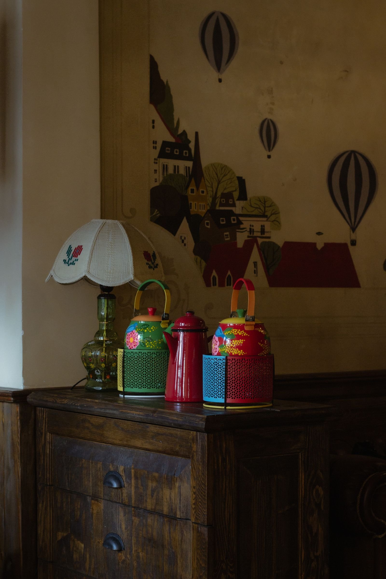 Colorful vintage tins and a lamp on a wooden cabinet.