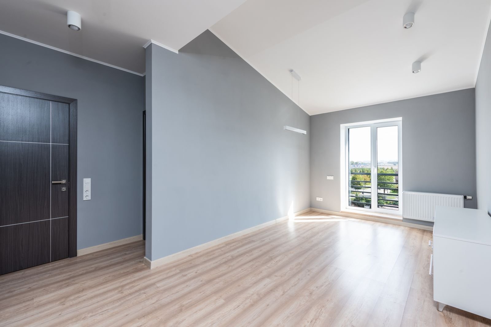 Minimalist room with gray walls, wood flooring and a large window.