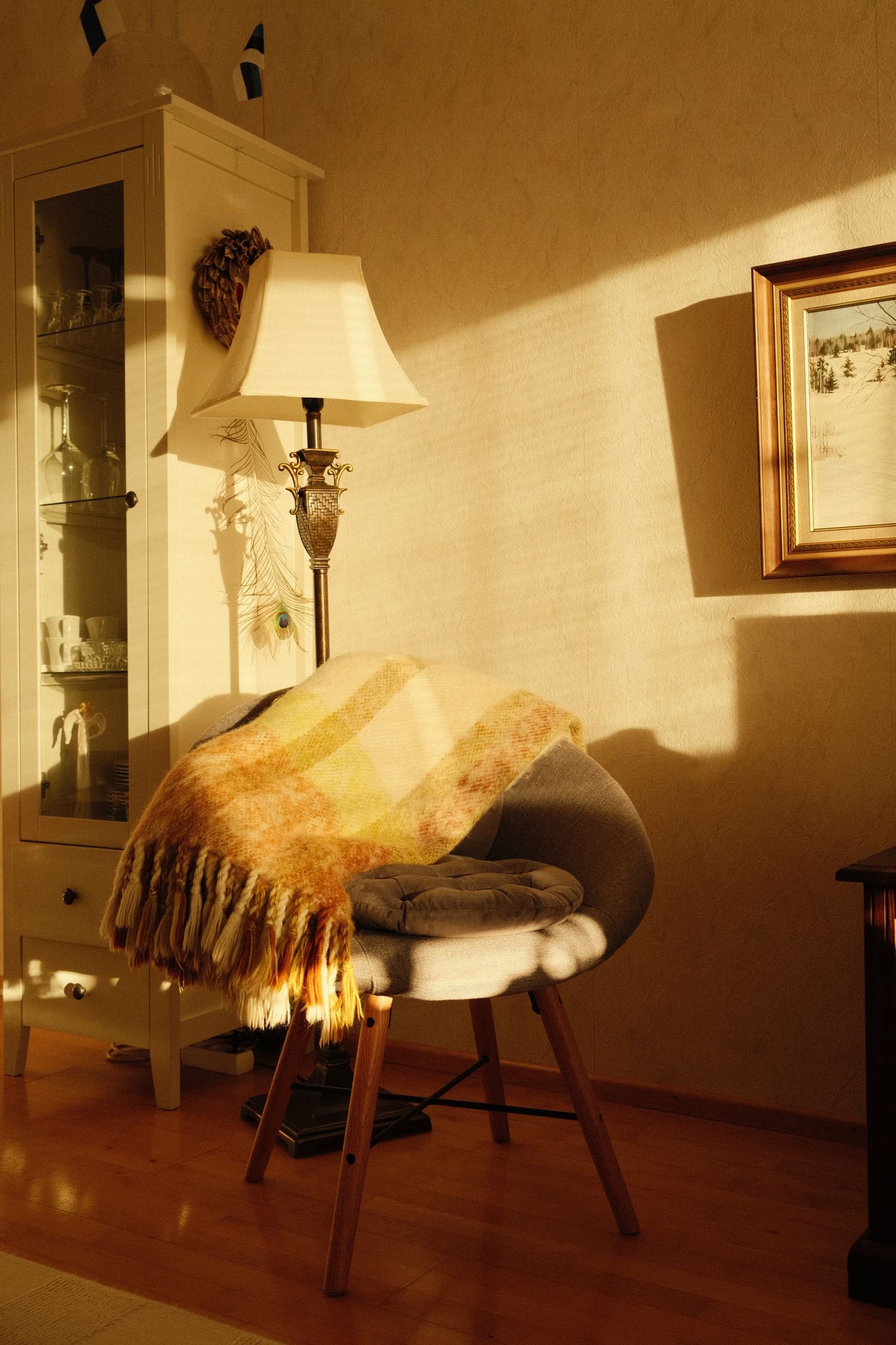 Cozy corner with a chair, a blanket and a warm lamp.