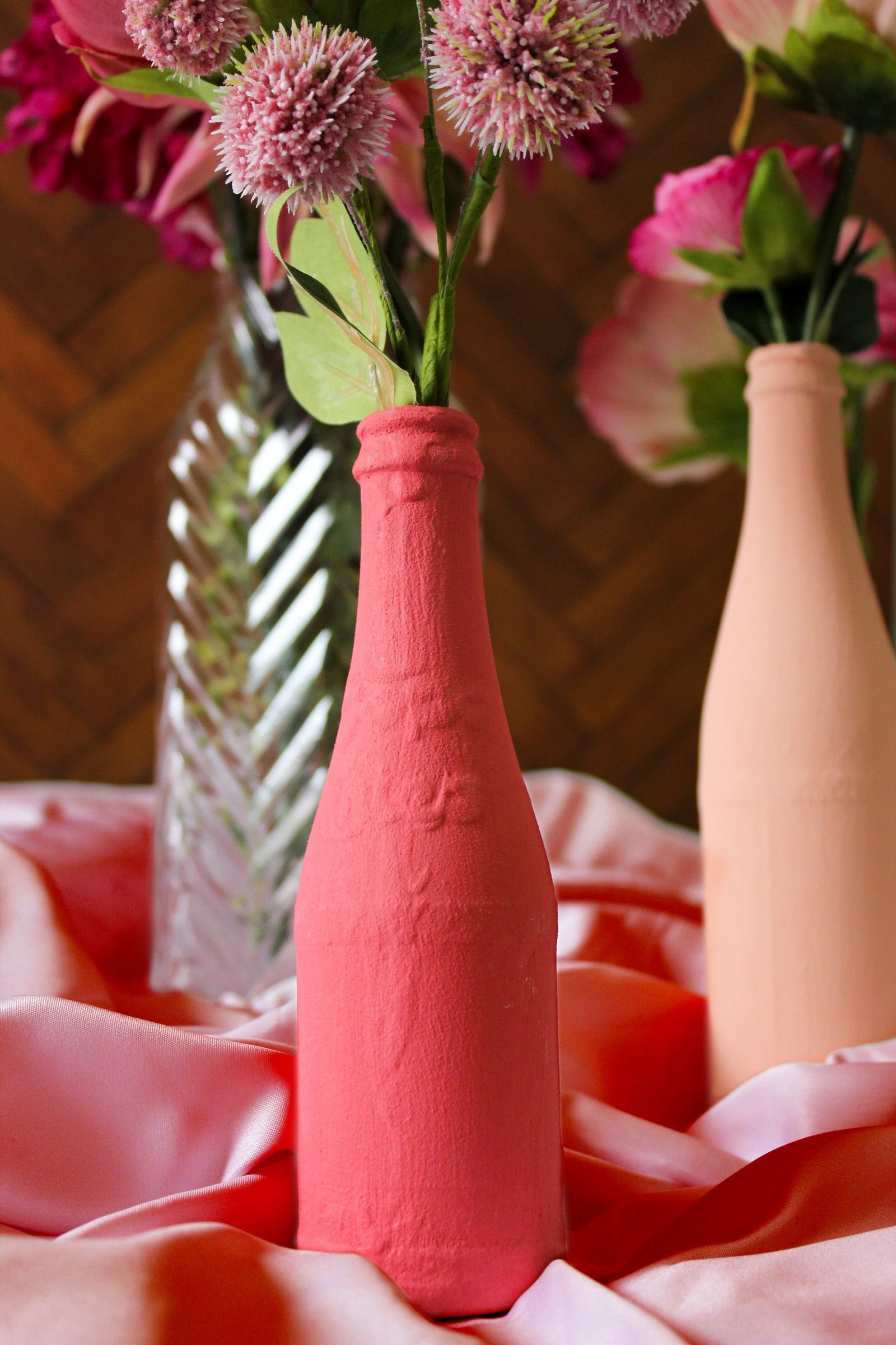 Flowers arranged in pink-painted glass bottles as a centerpiece.