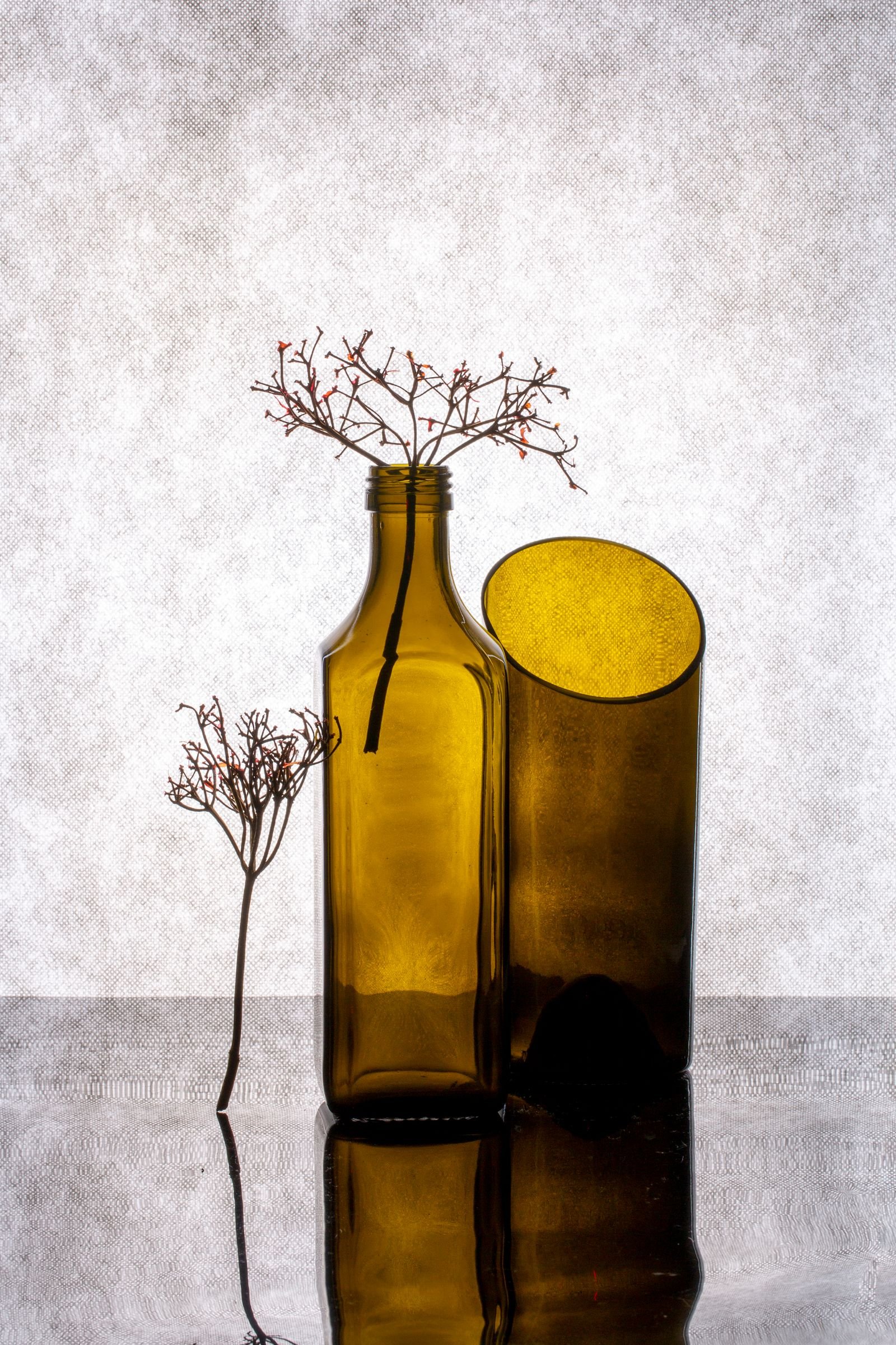 Amber glass bottles with dried branches in a minimalist arrangement.
