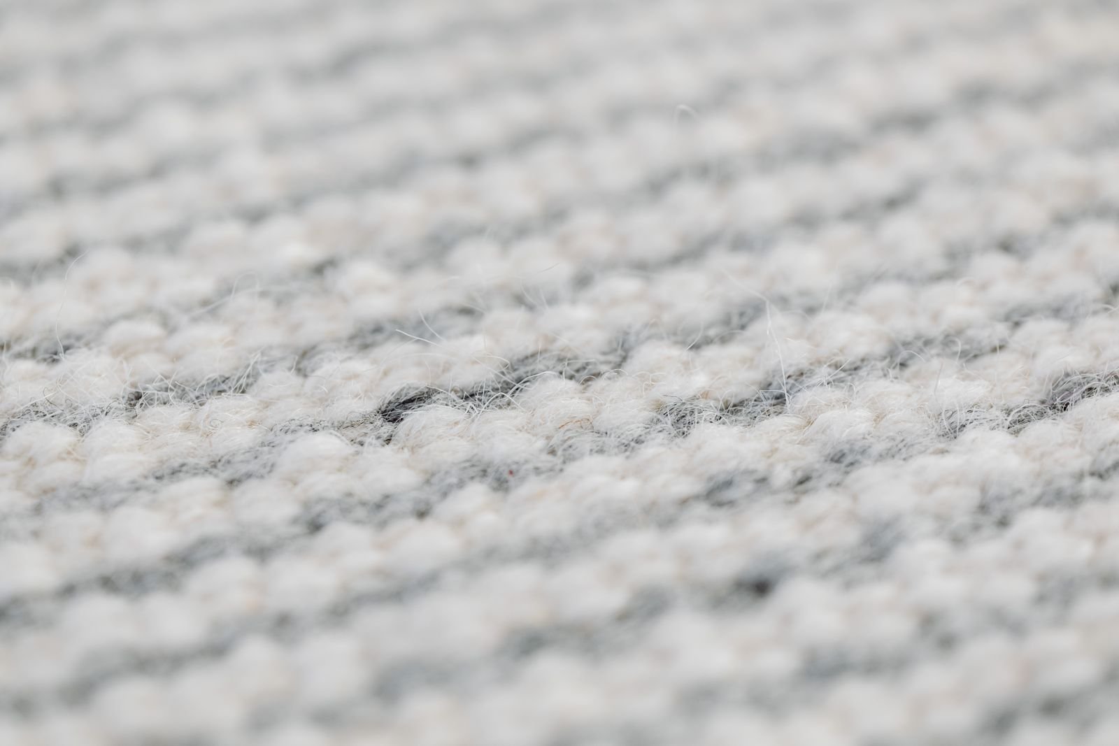 Close-up of a grey handmade wool rug showing its detailed weave.