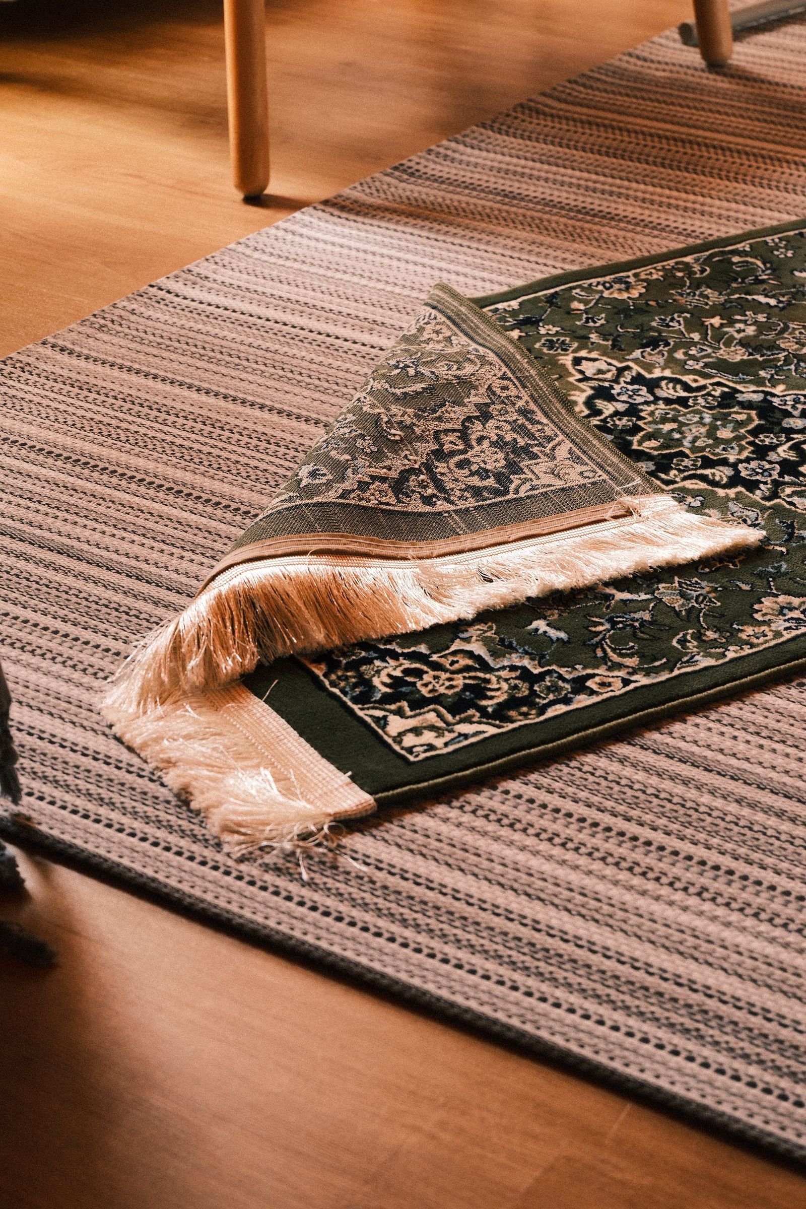 Layered woven and oriental rugs in a warm indoor setting.
