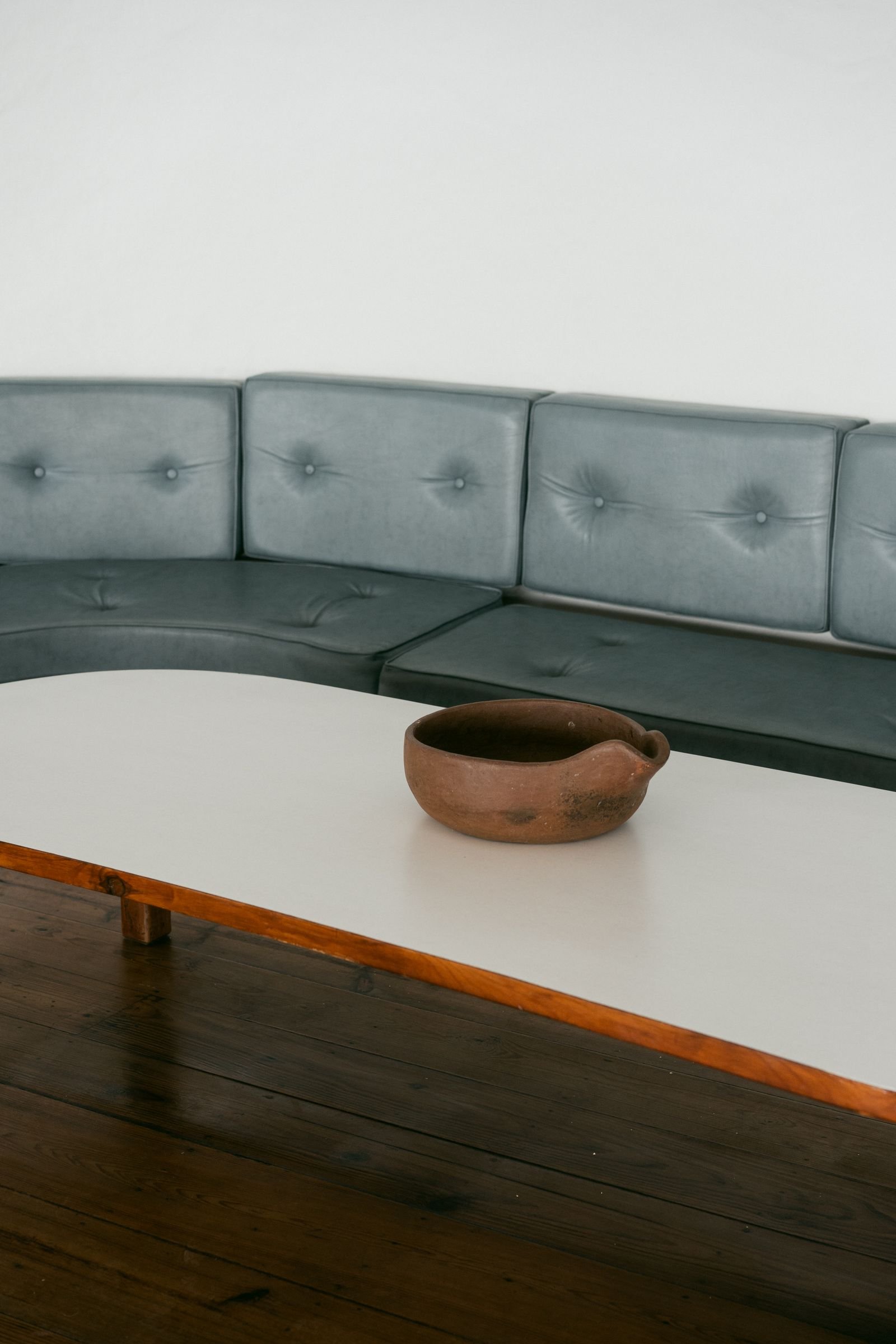 Minimalist living room with a curved sofa and a ceramic bowl in soft organic shapes