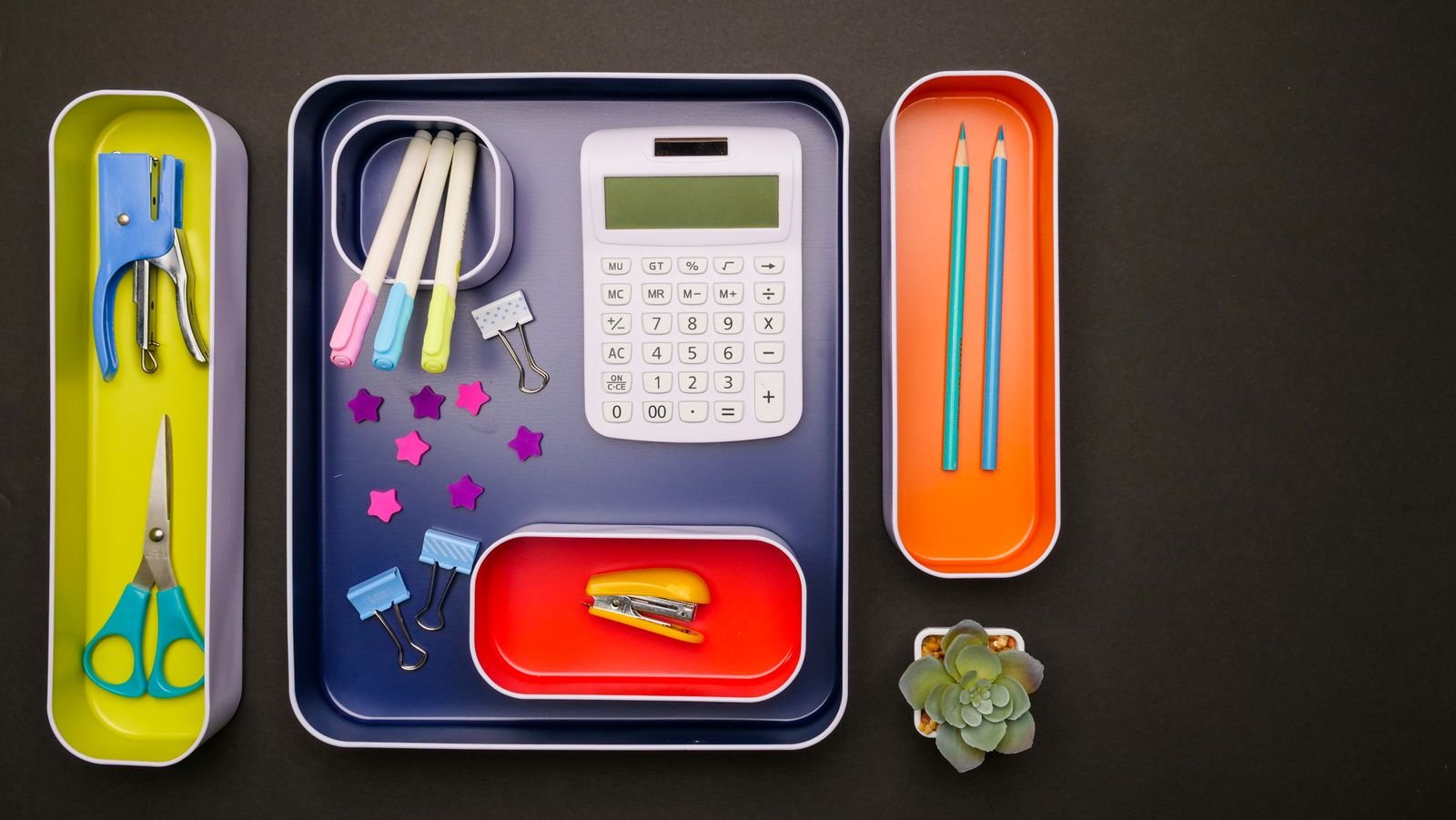 Desk accessories sorted into colorful trays for an organized workspace