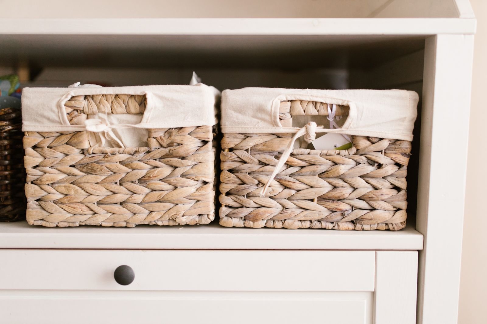 Woven baskets neatly arranged on a white shelf for home storage.