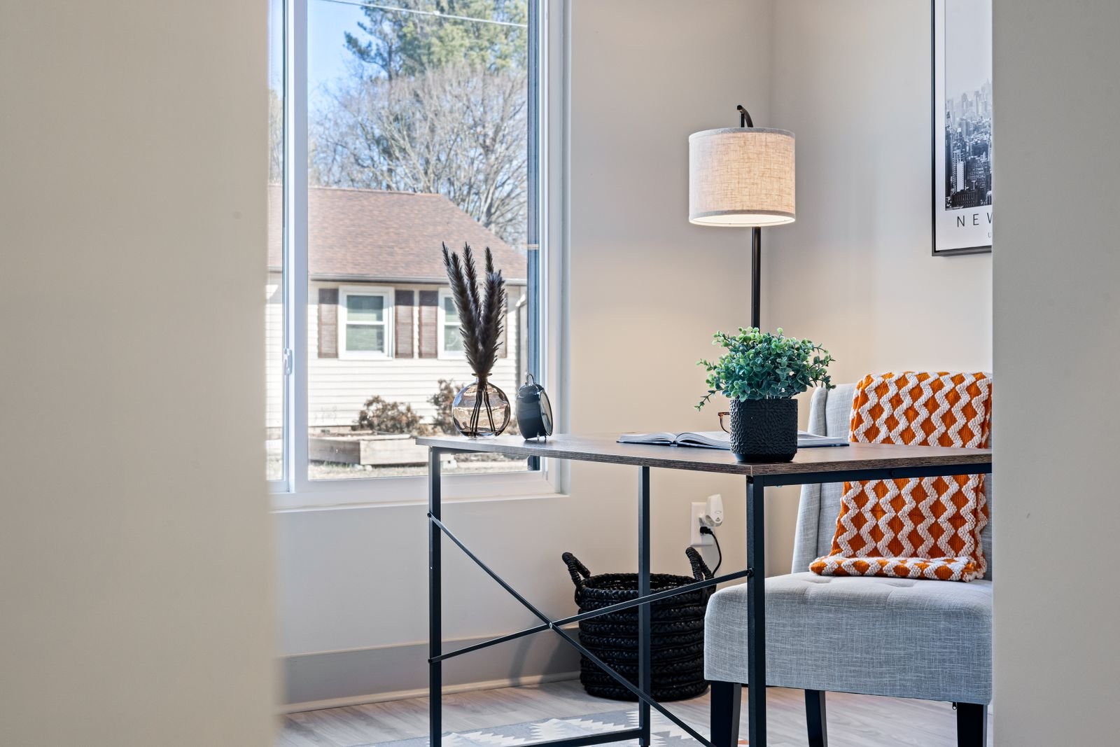 Bright home office nook with a minimalist desk, lamp and cozy blanket by the window