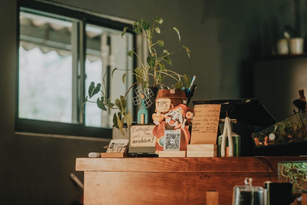 Warm cafe counter with tip box, potted plant, and handwritten notes, offering a cozy atmosphere.